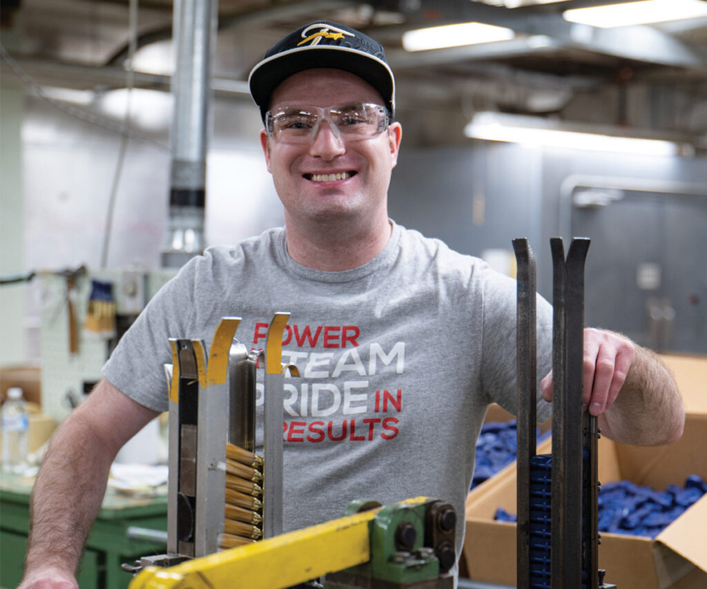 Smiling male employee working indoors with brushes and wearing safety goggles