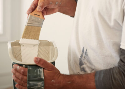 a man loading a paintbrush with white paint